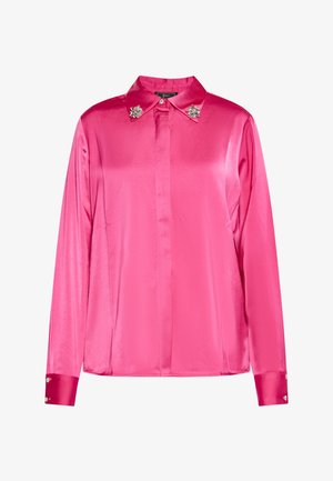 Roza satenasta majica z dolgimi rokavi z ovratnikom na gumbe, ki ima dekorativne akcentne kamenčke na ovratniku in gumbih manšete.