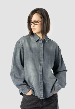 Denim shirt in faded gray, oversized fit with a button-down front, pointed collar, and long sleeves. Includes subtle stitching details.