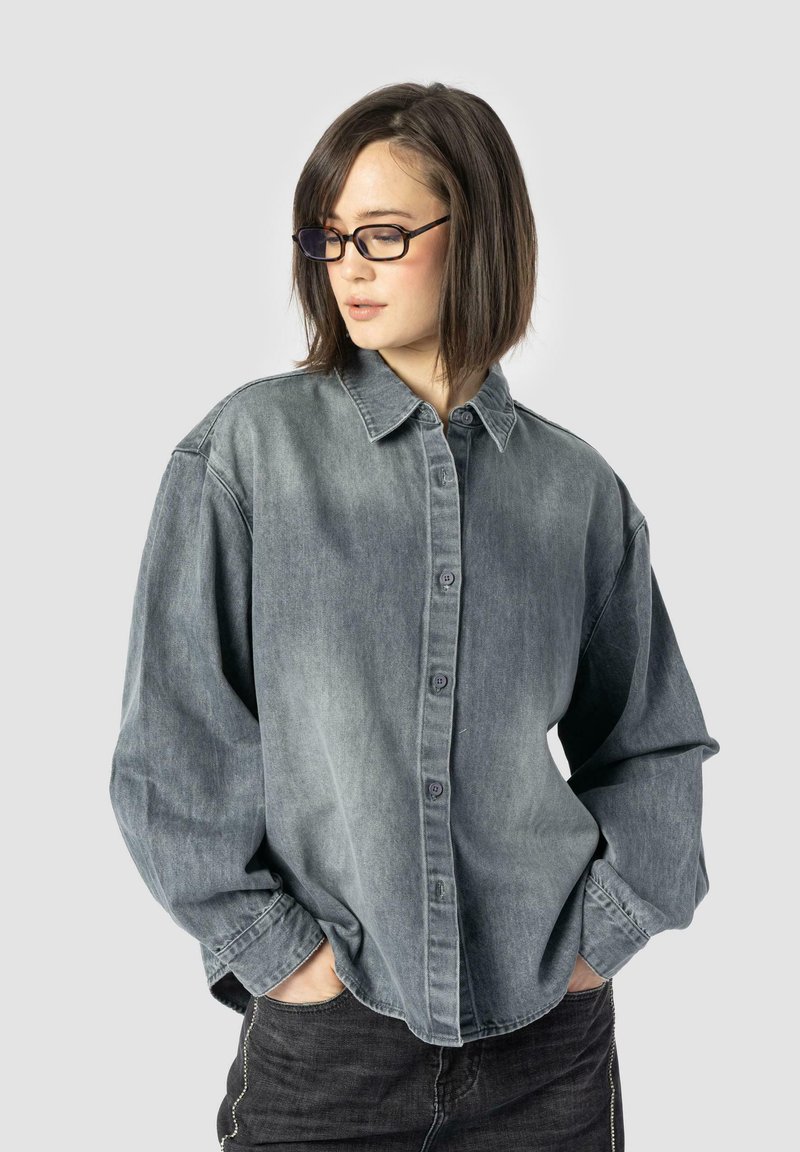 Denim shirt in faded gray, oversized fit with a button-down front, pointed collar, and long sleeves. Includes subtle stitching details.