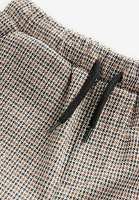 Mustriga jooksupüksid, millel on must-hall-beezh mustriga tikk, musta paela ja elastse talu.