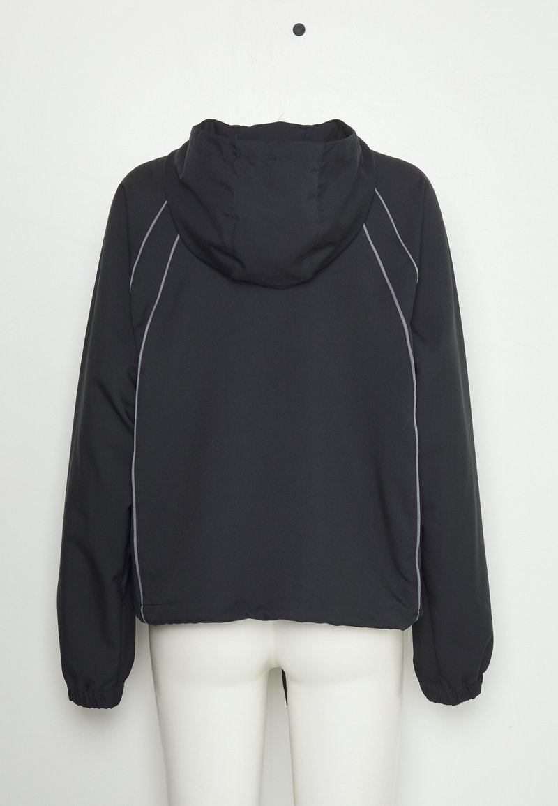 Chaqueta negra con capucha, de mangas largas y con piping gris a lo largo de las costuras, mostrada desde atrás en un maniquí blanco contra una pared lisa.