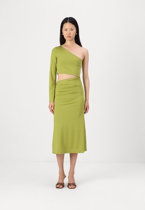 Vihreä, kahdesta osasta koostuva mekko, jossa on epäsymmetrinen yhdelle olalle oleva crop-top ja korkea vyötärö, polven pituinen hame, jolla on sileä rakenne.
