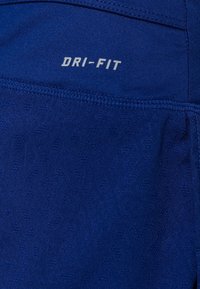 Sininen Dri-FIT-kangas, jossa on teksturoitu kuvio. Kankaassa on sileä pinta ja tikattu sauma.