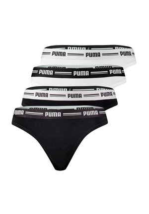 Smiling woman with curly hair wearing white Puma branded bra and matching underwear against plain gray background.