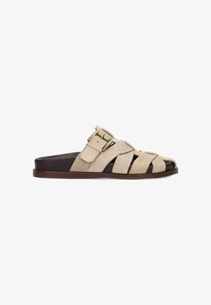 Sandale mule en daim beige avec bout ouvert, semelle marron foncé et bride réglable avec boucle dorée sur le dessus.