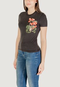 T-shirt nera a maniche corte con un design floreale che presenta fiori rosa e foglie verdi sul lato sinistro. Tessuto morbido e aderente.