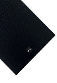Tappetino yoga rettangolare texturizzato nero con un piccolo etichetta nera che mostra simboli bianchi del controller PlayStation: triangolo e X.