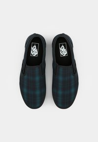 Černé slip-on boty s tmavomodrým kostkovaným vzorem a gumovou podrážkou. Interiér obsahuje logo na bílém pozadí.