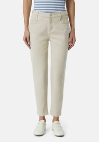 Beige Denimjeans mit slim fit, fünf Taschen und Knopfverschluss. Kombiniert mit weißen Sneakers und einem blau-weiß gestreiften Oberteil.