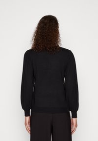 Svart strikket genser med lange pufferm, ribbede mansjetter og nederkant, glatt tekstur, tettsittende design og minimalistisk stil.
