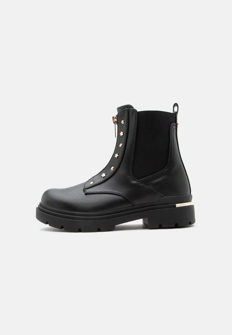 Bottine en cuir noire avec semelle épaisse, fermeture éclair latérale, panneau élastique et clous dorés en forme d’étoile le long du rabat de la fermeture éclair.