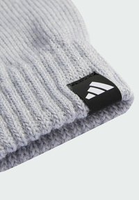 Siva pletena kapa s rebrastom teksturom i crnom adidas logotipom. Tkanina se čini mekom i blago sjajnom.