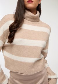 Beżowy i kremowy sweter typu golf w paski, z prążkowanym dekoltem, miękka tekstura, krótka długość, z długimi rękawami z wyraźnym wykończeniem mankietów.