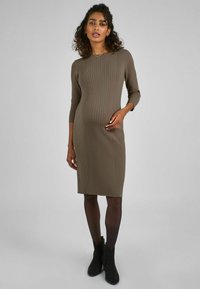 Ribbed-midi-mekko oliivinvihreänä, istuva malli, kolmiriviset hihat, helman lievä aaltoilu. Yhdistetty mustiin nilkkabootseihin.