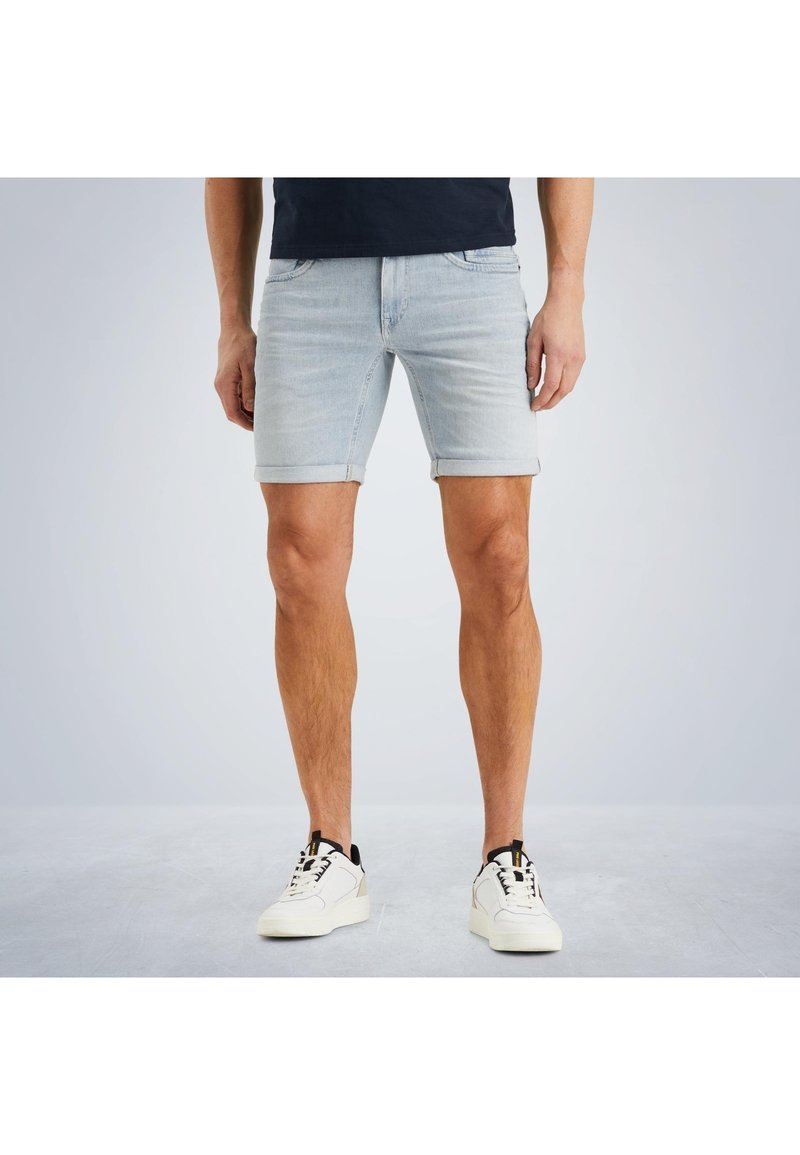 Helle blaue Jeansshorts mit umgeschlagenem Saum, im klassischen Fünf-Taschen-Design und mit Kontrastnähten, getragen mit weißen Turnschuhen.