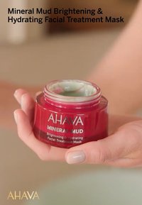 Rode pot met witte tekst, bevat een groene gezichtsbehandelingmasker. De tekst leest "Mineral Mud Brightening & Hydrating Facial Treatment Mask."