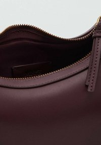 Burgundy leather handbag featuring a zipper closure, smooth texture, and gold-toned zipper hardware. Inner lining is dark fabric with logo.