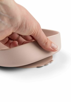 Silikonska skleda v mehki roza barvi z gladkim, zaobljenim robom. Roka drži skledo in prikazuje njeno prilagodljivo zasnovo ter podrobnosti na spodnji strani.