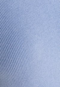 Ljusblå ribbad tyg med en mjuk, strukturerad yta. Mönstret har vertikala ränder som skapar subtil djup.