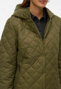 Oljčno zelena prešita jakna s kapuco, z gumbi na pritrditev, stranskimi žepi z zadrgo in vzorcem diamanta na teksturi blaga.