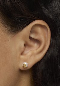 Złote kolczyki na sztyft z perłą, z motywem niedźwiedzia. Okrągły kształt, połyskująca faktura, osadzone w białej perle z złotym akcentem.