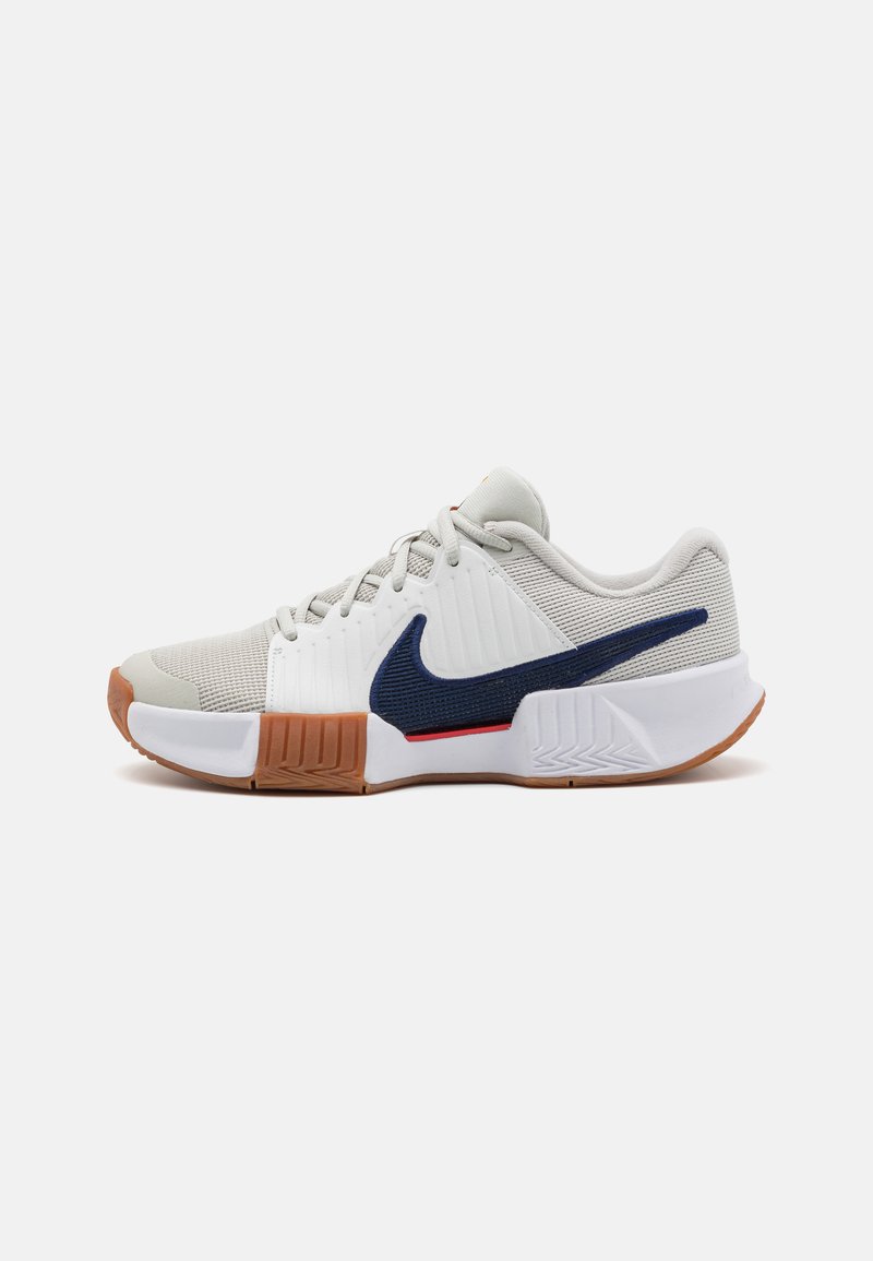 Nike athletic shoe with a grey mesh upper, white midsole, navy swoosh, and gum rubber outsole. Features textured detailing and laces.