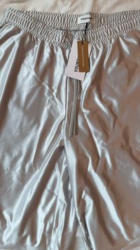 Silver athletic shorts made of recycled polyester. Elastic waistband with drawstring, featuring a smooth texture and a tag attached.