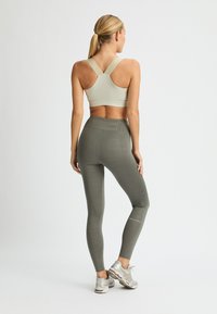 Leggings verdi con un motivo a griglia e un reggiseno sportivo di colore chiaro. I leggings presentano un design a griglia e il reggiseno ha una larga tracolla a incrocio.
