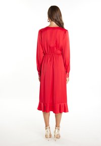 Abito in raso rosso con maniche lunghe, vita elastica e orlo arricciato. Include polsini con bottoni e una texture liscia e lucida. Collo alto.