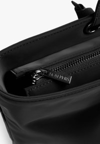 Interior de bolso de cuero negro con un compartimento con cremallera y tirador de cremallera plateado etiquetado "SCALPERS", textura suave y diseño limpio.