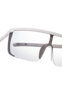 Urheilulasit, joissa on tyylikäs valkoinen kehys, harmaat yksityiskohdat ja läpinäkyvät linssit. Ominaisuuksiin kuuluu ympäriinsulkeva muotoilu laajennetun suojan saavuttamiseksi.