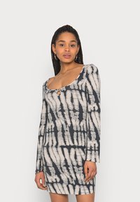 Vestido de manga longa feito de tecido elástico, com uma base cinza-escuro e padrões de pinceladas brancas, além de um detalhe com decote em forma de lágrima.