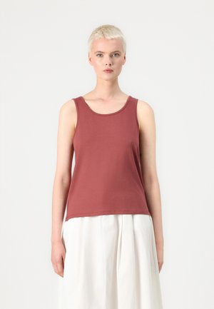 Débardeur bordeaux en coton doux avec un col rond et des bretelles larges, associé à une jupe blanche fluide. Design minimaliste.