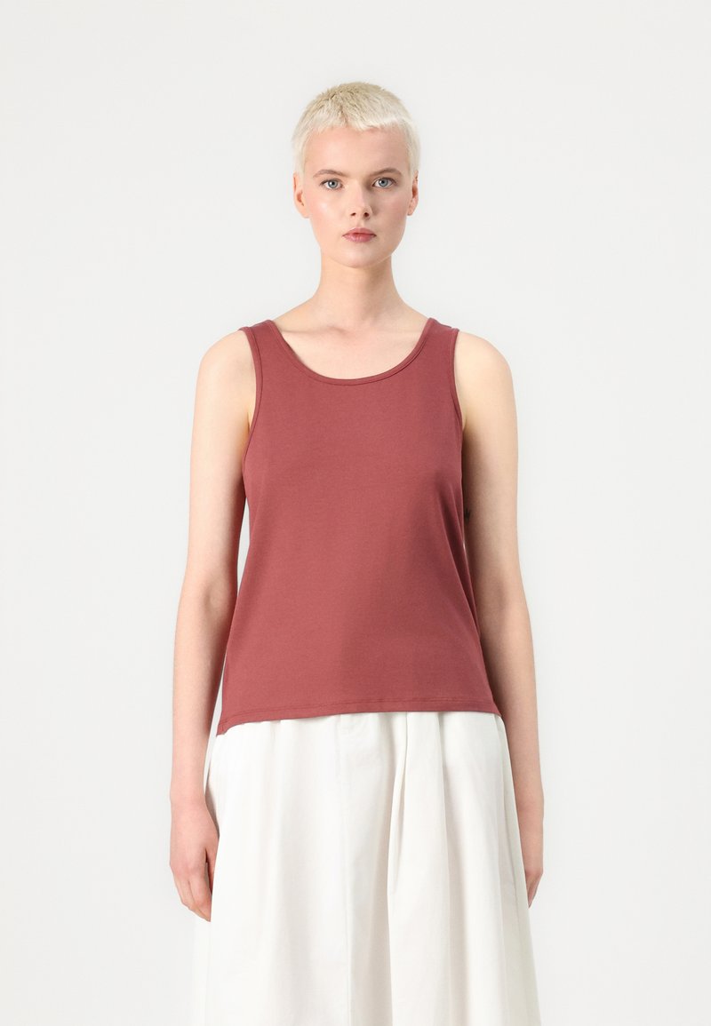Top de tirantes color marrón en suave tejido de algodón con escote redondo y tirantes anchos, combinado con una falda blanca fluida. Diseño minimalista.