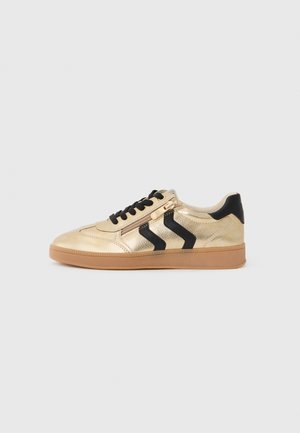 Sneaker metallico dorato con accenti neri e design a zigzag, dotato di lacci neri e suola in gomma naturale. Chiusura laterale con zip per indossarlo facilmente.