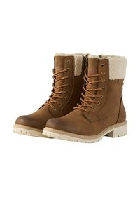 Bottes chelsea en cuir marron avec col en fausse fourrure, fermeture à lacets à l'avant et semelle en caoutchouc texturée crème. Présente des éléments en métal et des détails de couture.