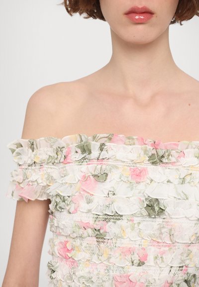Off-the-shoulder floral top featuring ruffled layers, primarily in white with pink and green accents, crafted from lightweight fabric.
