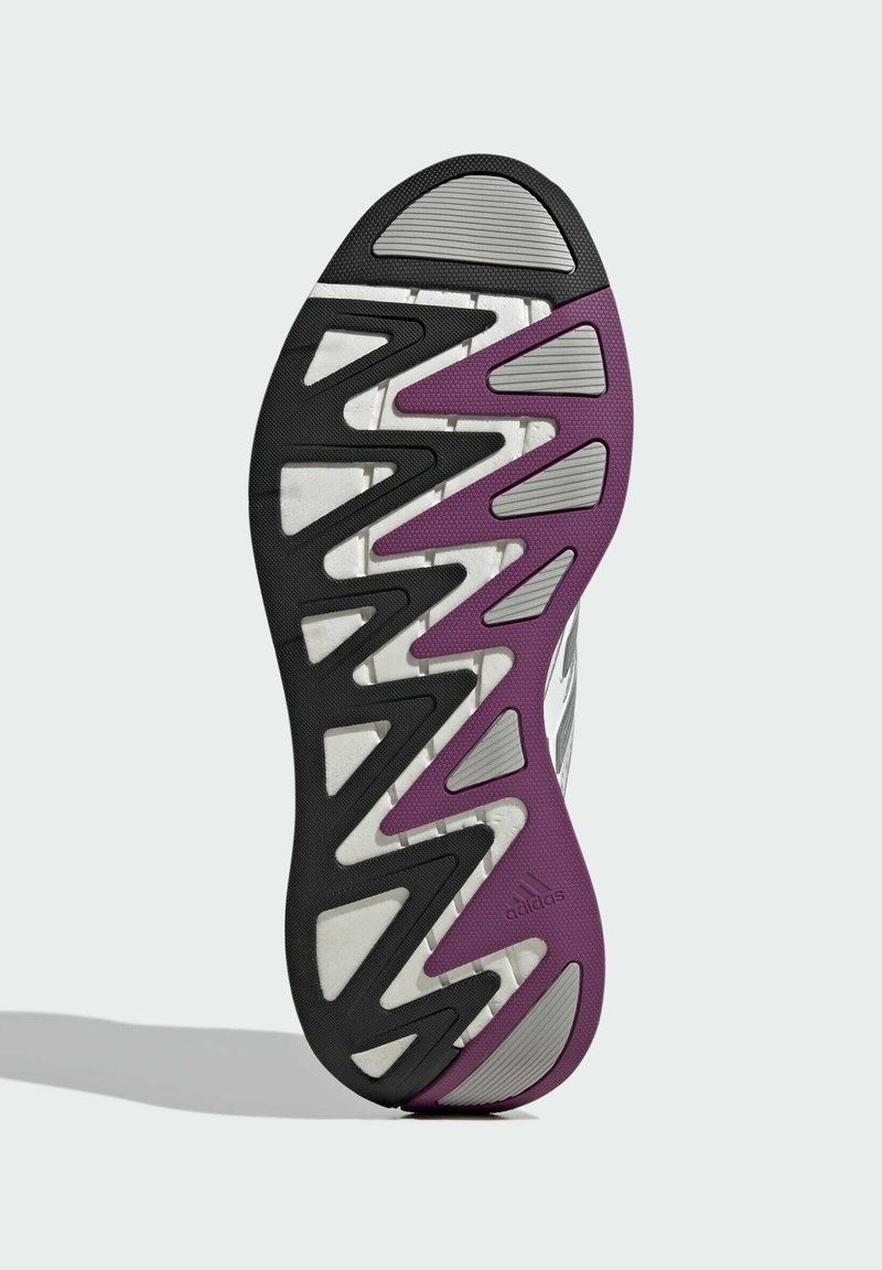 Semelle de chaussure de sport noire et violette avec des motifs en zigzag, une texture antidérapante et une section lisse blanche avec des accents argentés.