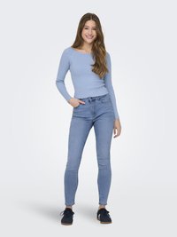 Light blue ribbed long-sleeve top with a square neckline paired with fitted light blue jeans and dark blue sneakers.
