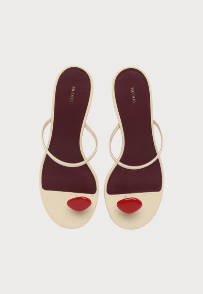 Paire de sandales crème avec semelles bordeaux, brides fines et grands ornements ovales rouges sur la zone des orteils, vues de dessus.