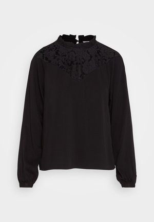 Zwarte blouse met lange mouwen, kantdetail op de schouder, lichte ruches bij de kraag en een losse pasvorm. Zachte textuur, effen kleur.