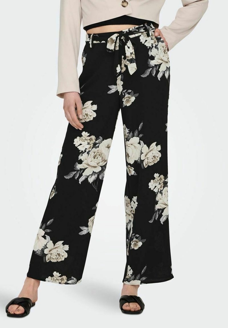 Pantalons larges à fleurs en tissu noir avec de grandes fleurs crème et grises. Comprend une taille à nouer pour un ajustement ajustable.