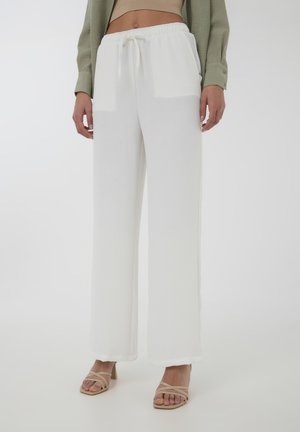 Pantaloni bianchi a gamba larga con un tessuto testurizzato e una vita elastica, abbinati a tacchi beige con cinturini.