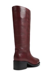 Bota de couro burgundy até ao joelho com bico arredondado, costuras verticais e um salto preto robusto. Textura suave em toda a superfície.