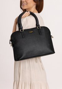 Black leather handbag with a structured shape, gold hardware accents, double top handles, and a textured finish. Zippered closure at the top.