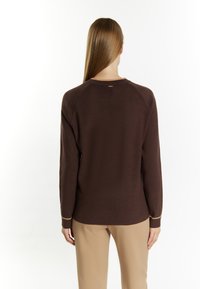 Brauner Langarmpullover mit Raglanärmeln, der am Bund und am Kragen einen Akzent in hellerer Farbe aufweist. Weiche Textur, schmaler Schnitt.