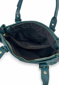 Sac à main en cuir bleu sarcelle avec une finition texturée. L'intérieur comprend une doublure en tissu noir, des compartiments zippés et plusieurs poches pour l'organisation.