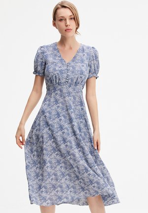 Robe bleue à fleurs avec des manches courtes bouffantes, un décolleté en V et une jupe fluide de mi-longueur. Tissu léger avec un motif texturé subtil.