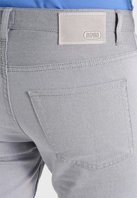 Grå mönstrade chinos med en texturerad yta, med en bakficka och en plastlogotyp som heter "BOSS."