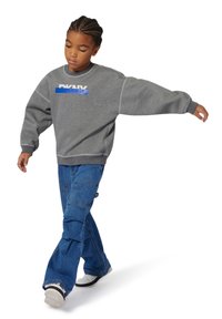 Sweatshirt gris avec logo DKNY en bleu, associé à un pantalon cargo large bleu. La tenue présente une coupe décontractée et un design casual.